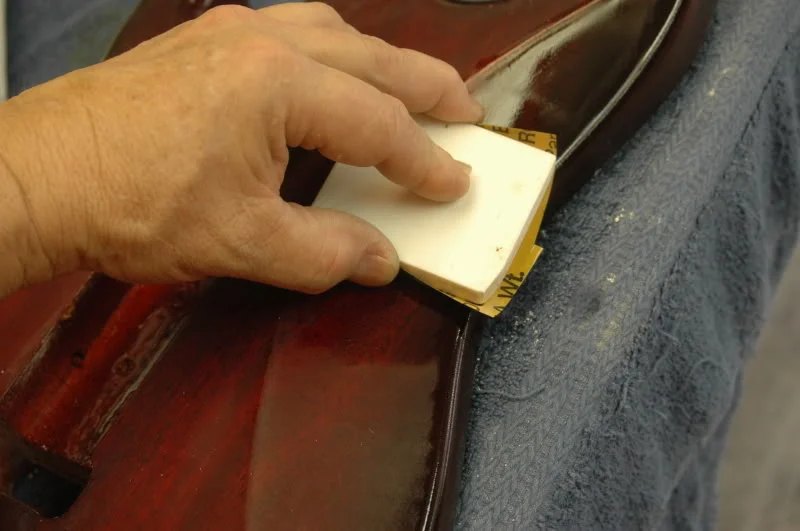 As you’re looking for the low spots, they tend to be along the edge, they can be quickly removed by hand sanding, but doing so will result in a less than Plano-flat surface. If you continue using the block on those areas, your final gloss will be virtually mirror flat. To do concave curves, I made a slight rounded block, this one is made from Corian.
