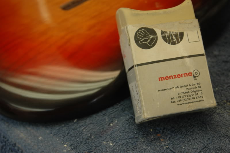 The fine polishing compound is usually identified by a white color; here I'm using a compound stick, its compound suspended in a "wax" substrate. You simply "charge" the buffing wheel by holding the stick against it for a few seconds.