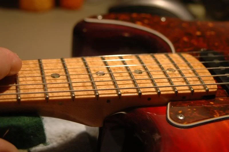 Now I recheck action in the vicinity of the 15th fret, raising or lowering each saddle respectively until I detect a bit of buzz. I then raise the saddle a full turn of the setscrew in the saddle, to give slightly more than enough clearance.