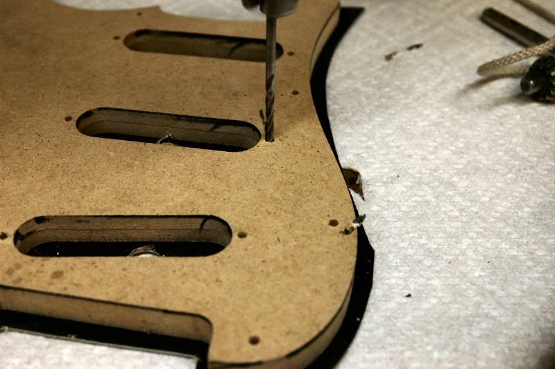  When drilling laminated pickguard material, use a fresh backing. If your table is full of old holes, the downward pressure from the drill press can cause the surface lamination to separate and pop loose. It’s not repairable, so use something under t