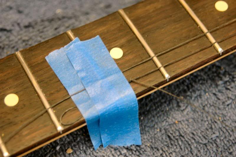  Now, it’s time to place the string retainer. I use a high precision tool to simulate the location of the 1st and 2nd strings… a string. I tape it to the fingerboard, run it down across the 1st string nut slot, around the key, loop it under and aroun