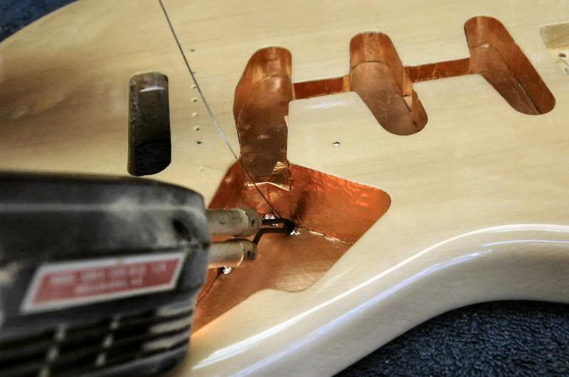  I begin soldering in the electronics cavity. IMPORTANT - quick fast heat here. The back of the guitar is only about 1/8th inch away. Go nuts with the solder gun, and you will also go nuts when you flip it over only to discover burnt, bubbled lacquer