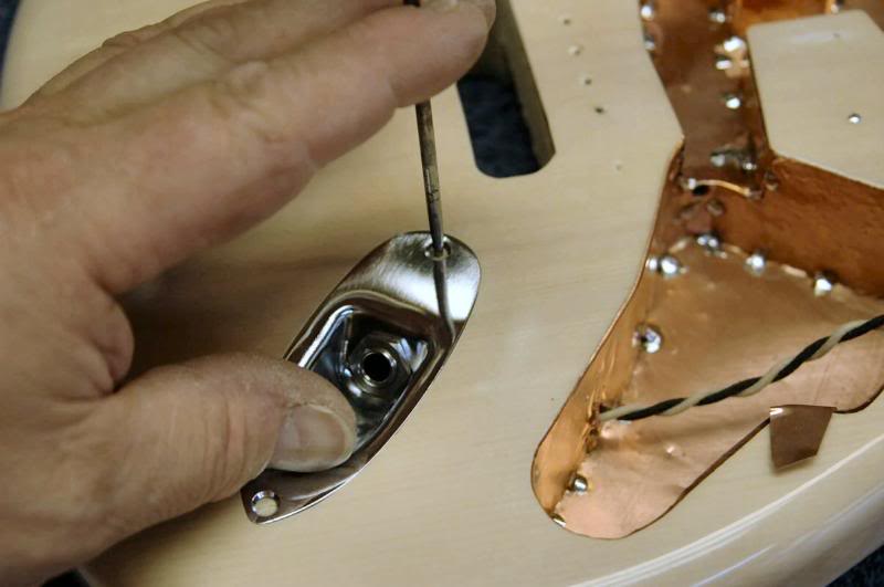  I take an awl and locate the start point for the screw. Remember, it’s recessed and I don’t want the countersunk screw off center shoving the plate into the edge of the recess… crack!!!! BTW, I forgot to photograph soldering the pickguard and relate