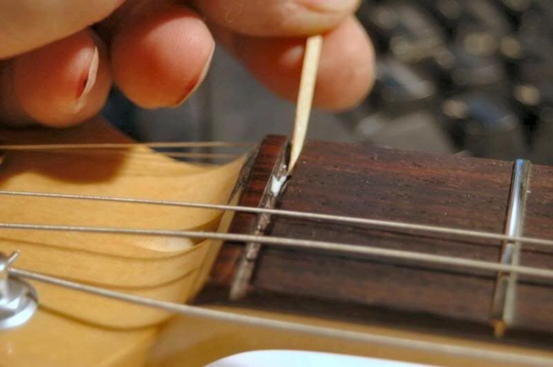  Just a touch on each end of the slot, about at the location of the 2nd and 5th strings, and run a small line between them. That’s it. Slip the nut into the slot, clean any ooze that may squeeze out, and tune ‘er up. 