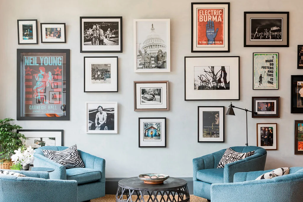 Picture of a sitting area designed by CLOTH & KIND in Athens, GA with four blue chairs, a metal coffee table, and framed vintage art and posters on the wall. Text on the image reads "Lyceum".