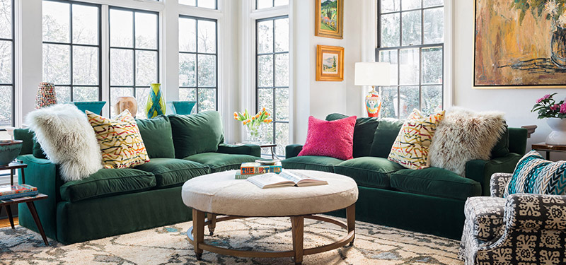 Picture of a living room designed by CLOTH & KIND in Athens, GA with two green couches, a white fuzzy coffee table, black and white pattered chair, large window and art. Text on the image reads "Westlake Update".