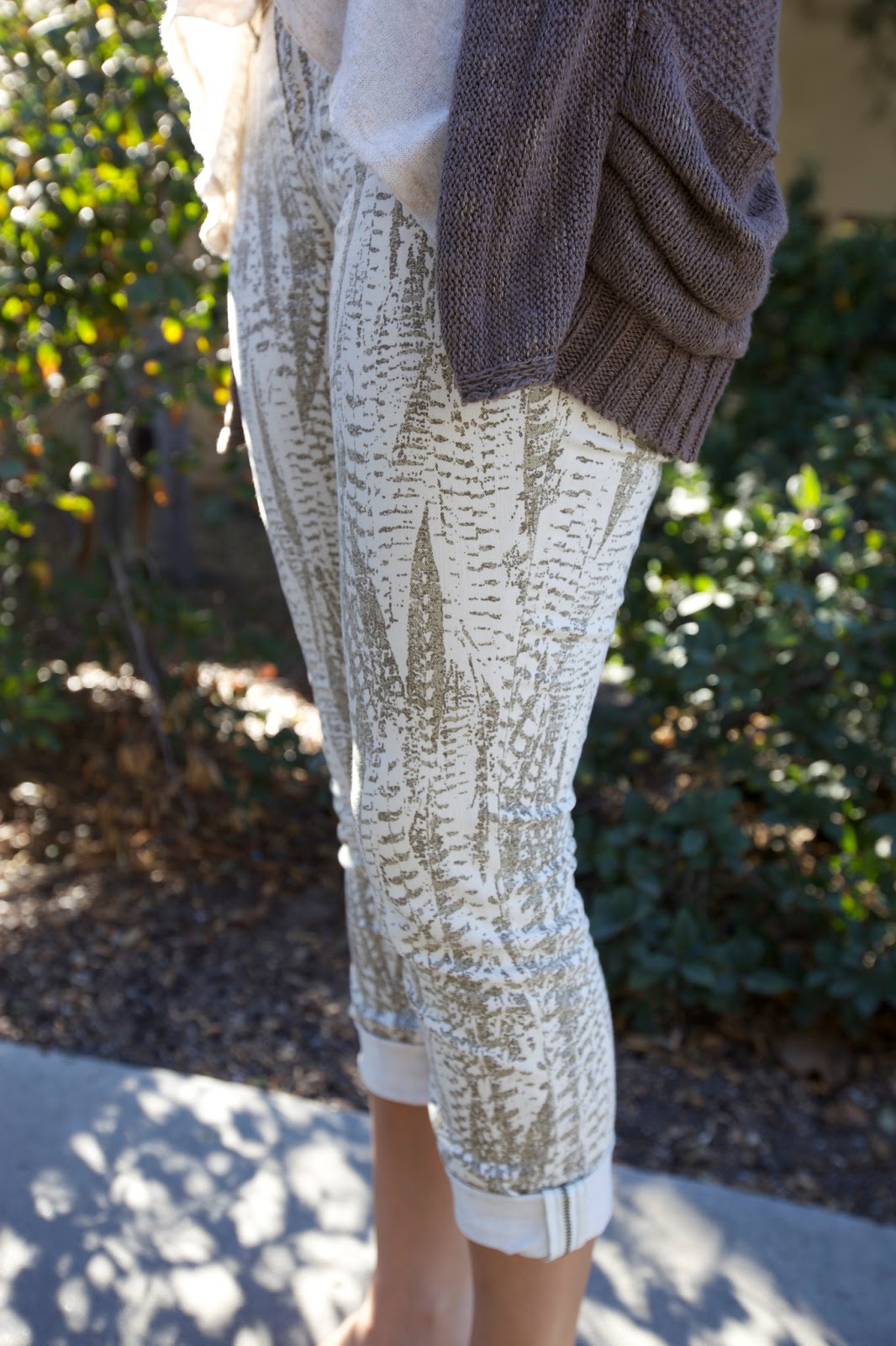 Miruna, a Santa Clara University student wears a stone gray cardigan over a ruffle white scoop top and leaf nature print white and sand leggins
