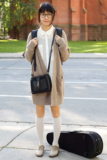 University of toronto student walks to her violin music class wearing a beige maroon oversized buttonless cardigan over a white shirt and paired with knee length white socks and ash gray suede laced shoes