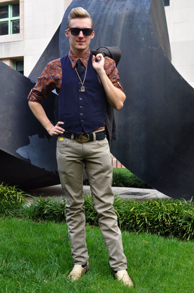 Columbia Student Zach wears a floral print shirt under a blue corduroy vest and over a pair of light gray jeans and golden sneakers