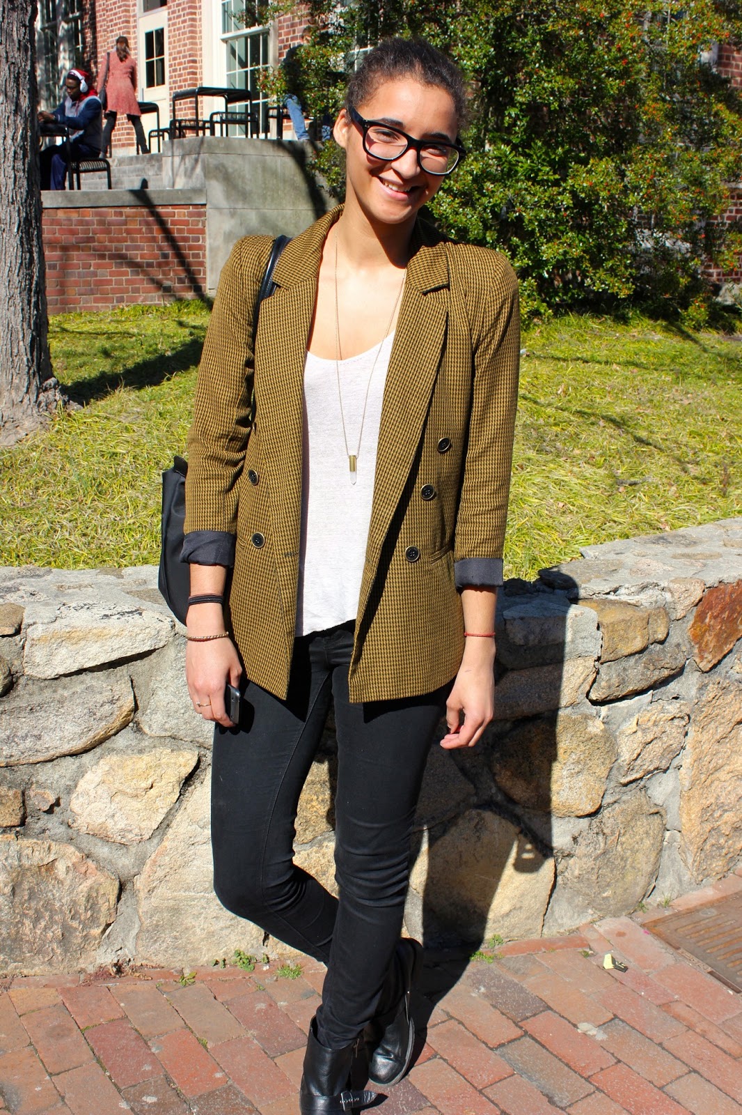 University of North Carolina in Chapel Hill student wears a vintage black and yellow houndstooth tweed blazer sleeves rolled up over a simple white scoop neck tee slim black jeans and black leather combat boots.