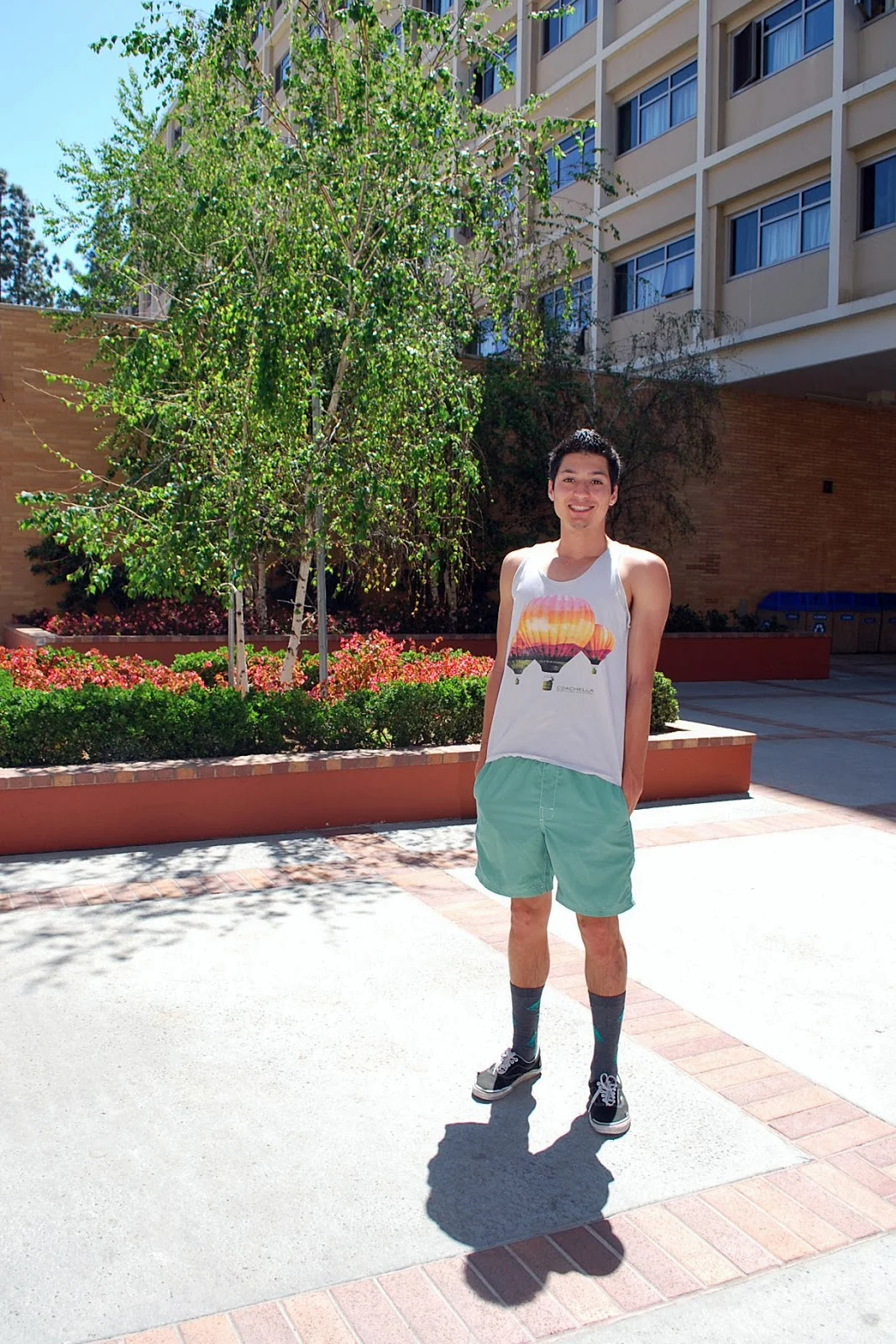 Max is a 1st Year student studying Civil Engineering. He is wearing a gray Coachella balloon print tank top over green shorts and green T-rex dinosaur socks and black vans
