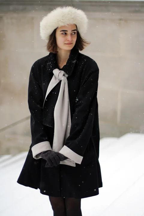 Harvard - Anna Roth wearing a white fur hat and a black coat with gray lining