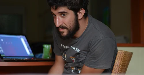 Thanasis Karavasilis sitting at a table with his writing tools