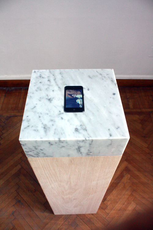   Proposal for a Romantic Sculpture, 2012, Video embedded in a sculpture. Video: 5 min. loop on iPod/iPhone, commissioned tattoo of song title ‘ne me quitte pas‘ by Jacques Brel. Sculpture: 29 x 29 x 100 cm, marble and wood (Photo: GANZEER).  