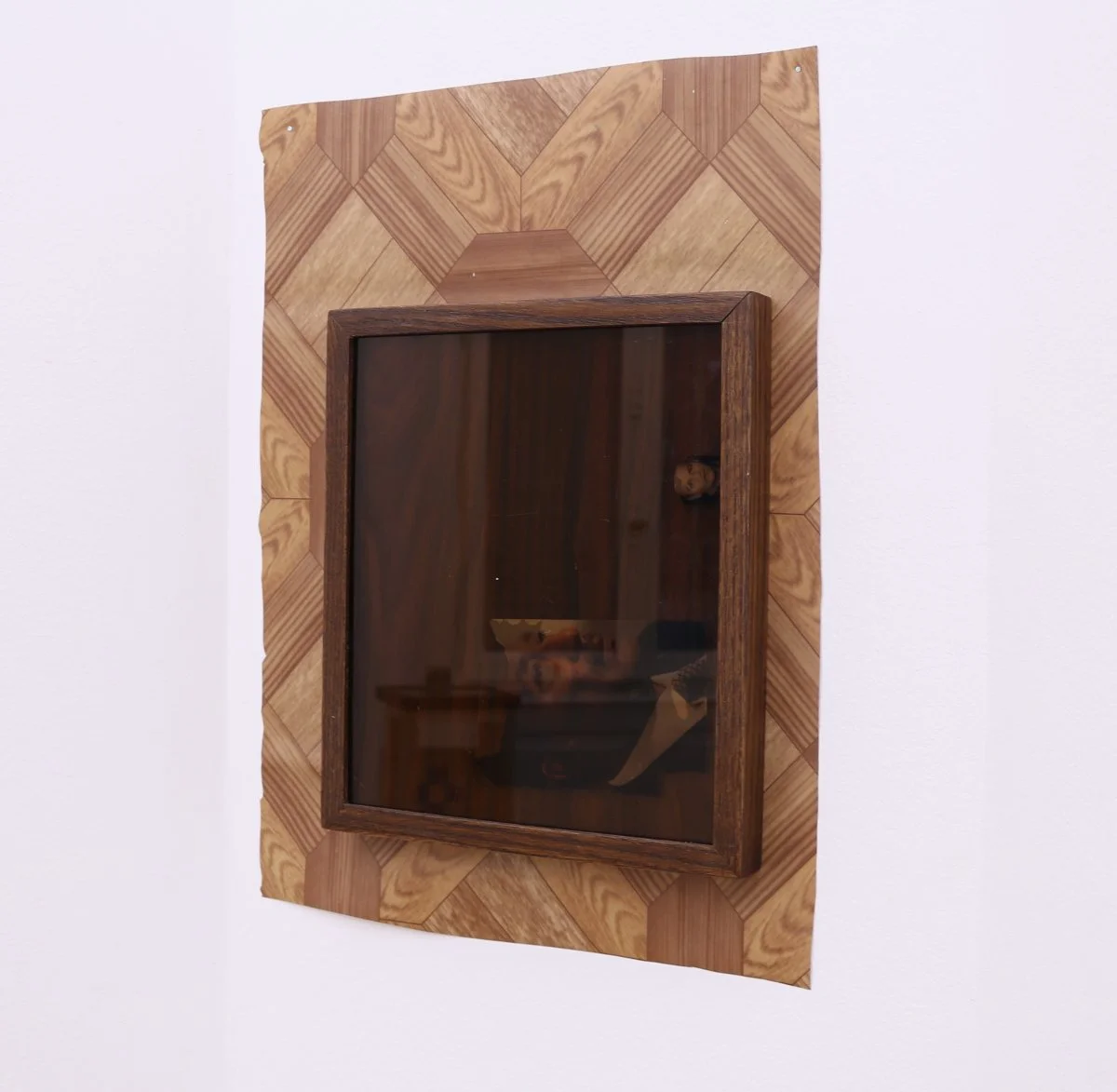 Untitled (clue), 2016, variable dimensions, PVC flooring on wall, wood frame (25 x 30 cm) with tinted glass and found photographs of uncle and Sadat, faux wood laminate backing.
