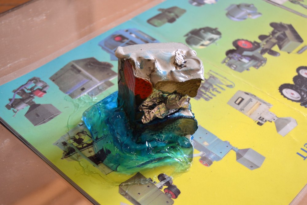  Paperweight #1, detail, 2015/16, Installation view, materials: Concrete with cardboard, aluminium foil and expanded foam, blue "Hair Code" gel, laminated company brochure (installation view), Roughly 6 x 6 x 6 cm. Photo: Nile Sunset Annex 