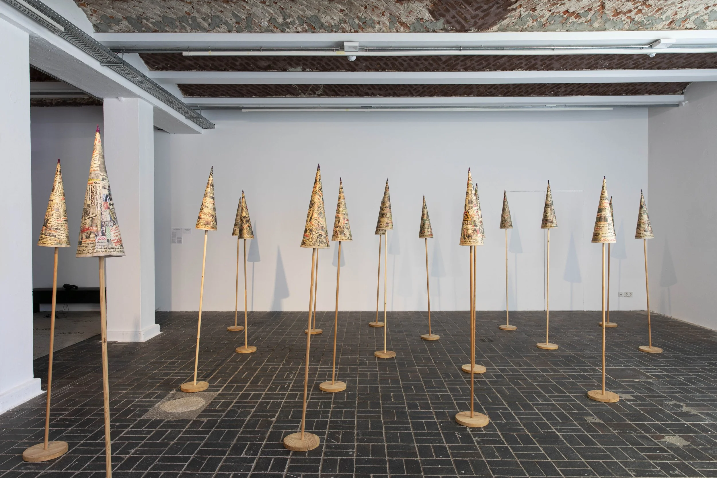  Installation view, 13th Berlin Biennale, KW Institute for Contemporary Art, 2025   The Fool’s Journal , 2013-14, Installation of newspaper cut-outs on fabric and wood, 18 collage pieces: 60 cm H x 22 cm diameter, 35 square meters space  Image: Diana