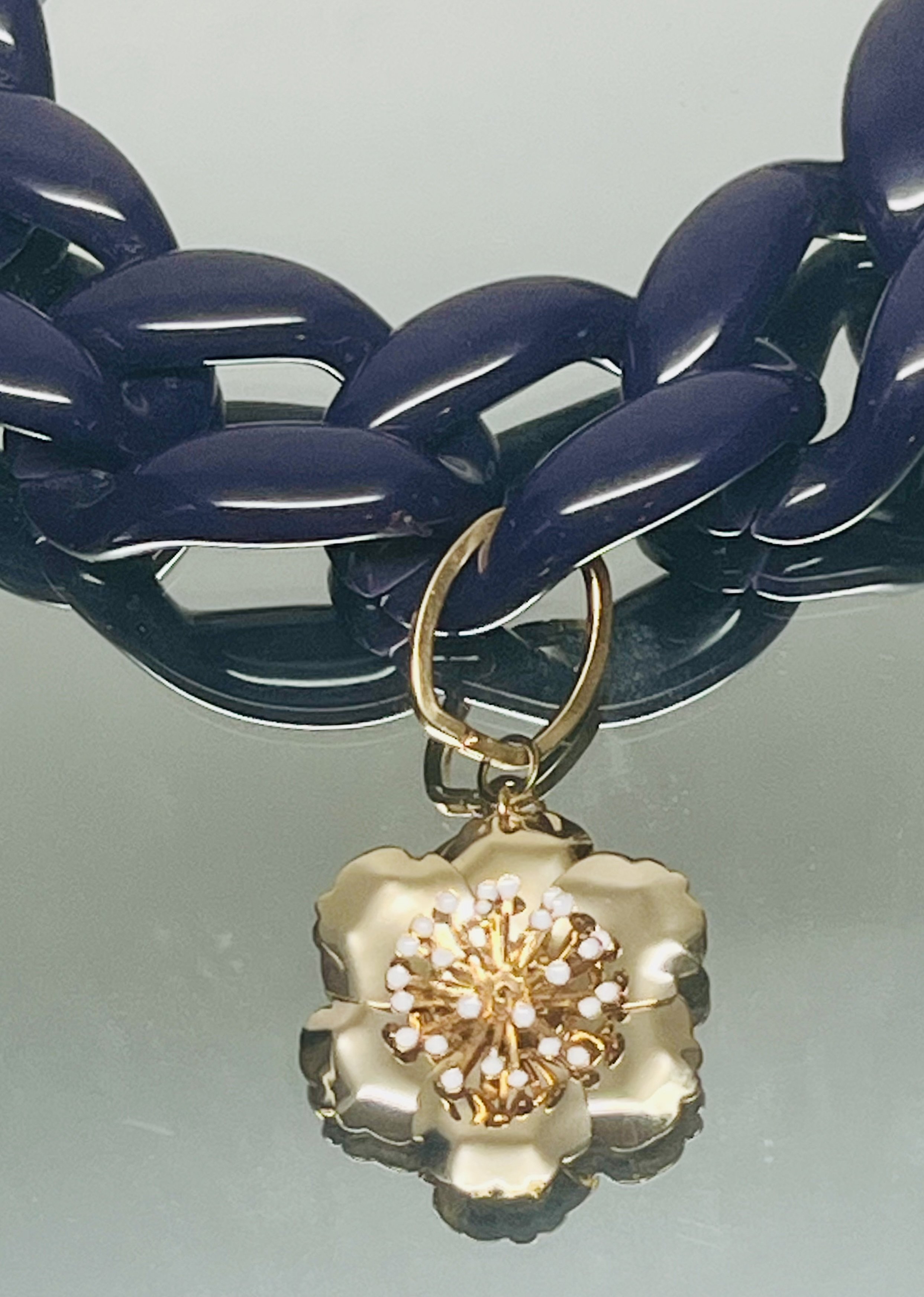 Close-up of a gold and pearl brooch with intricate flower design placed on a light reflective surface.