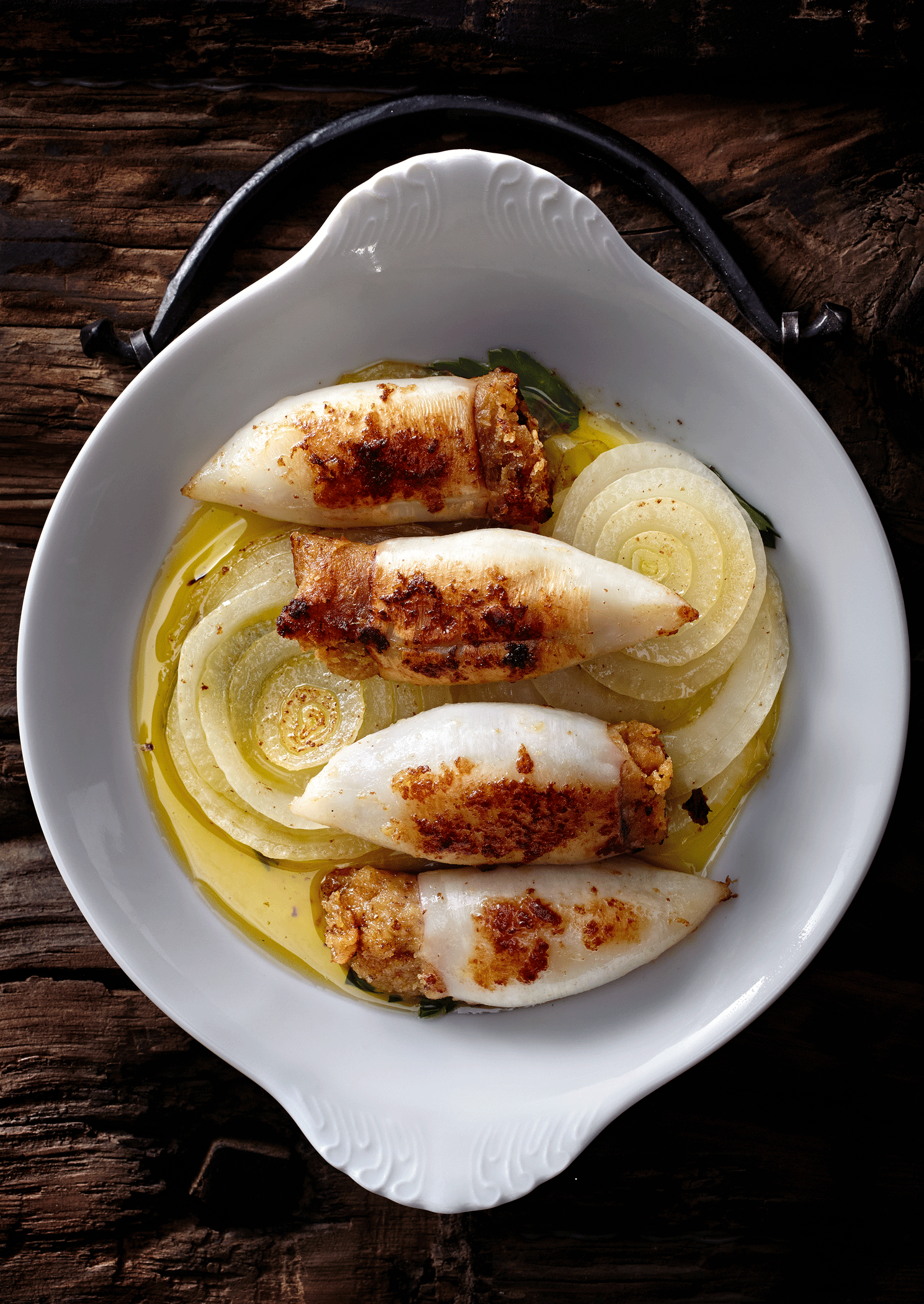 Ingredients 1⁄2 cup plus 2 tbsp. olive oil, 1⁄4 tsp. dried oregano, 1 clove garlic, finely chopped, 1⁄4 white onion, 4 cleaned calamari, 1 cup bread crumbs, 1 cup finely grated pecorino, 3 tbsp. finely chopped parsley, 2 tbsp. finely chopped oregano, Kosher salt and freshly ground black pepper, to taste