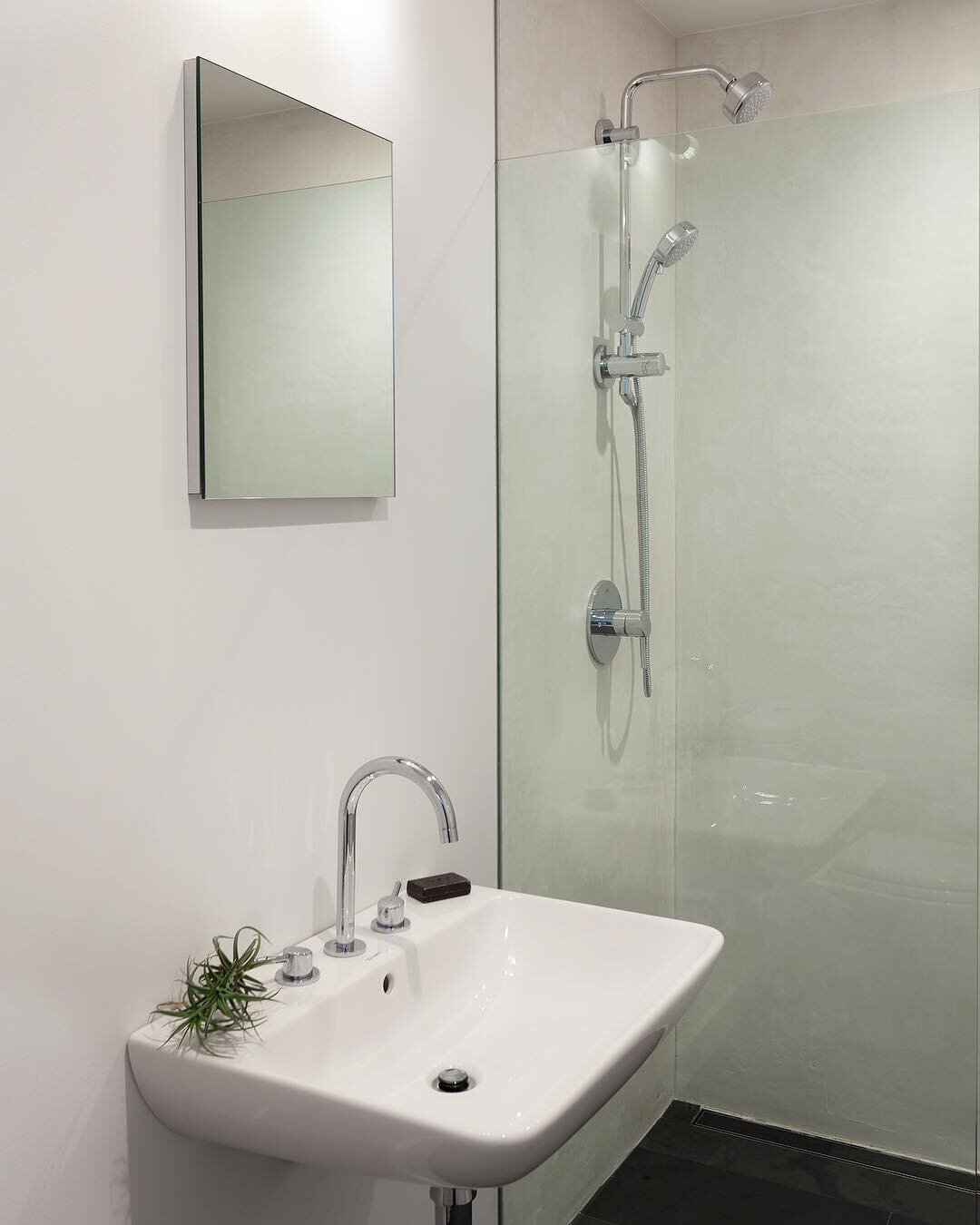 This ultra minimalist wheelchair accessible bathroom in one of our recent projects has smooth black slate floors, concrete walls, and a curbless roll-in shower. Complimented with Grohe fixtures.