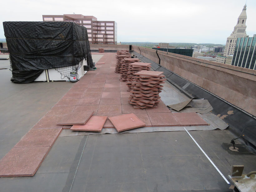 Installing brick-colored concrete pavers for ballast on an EPDM roof.