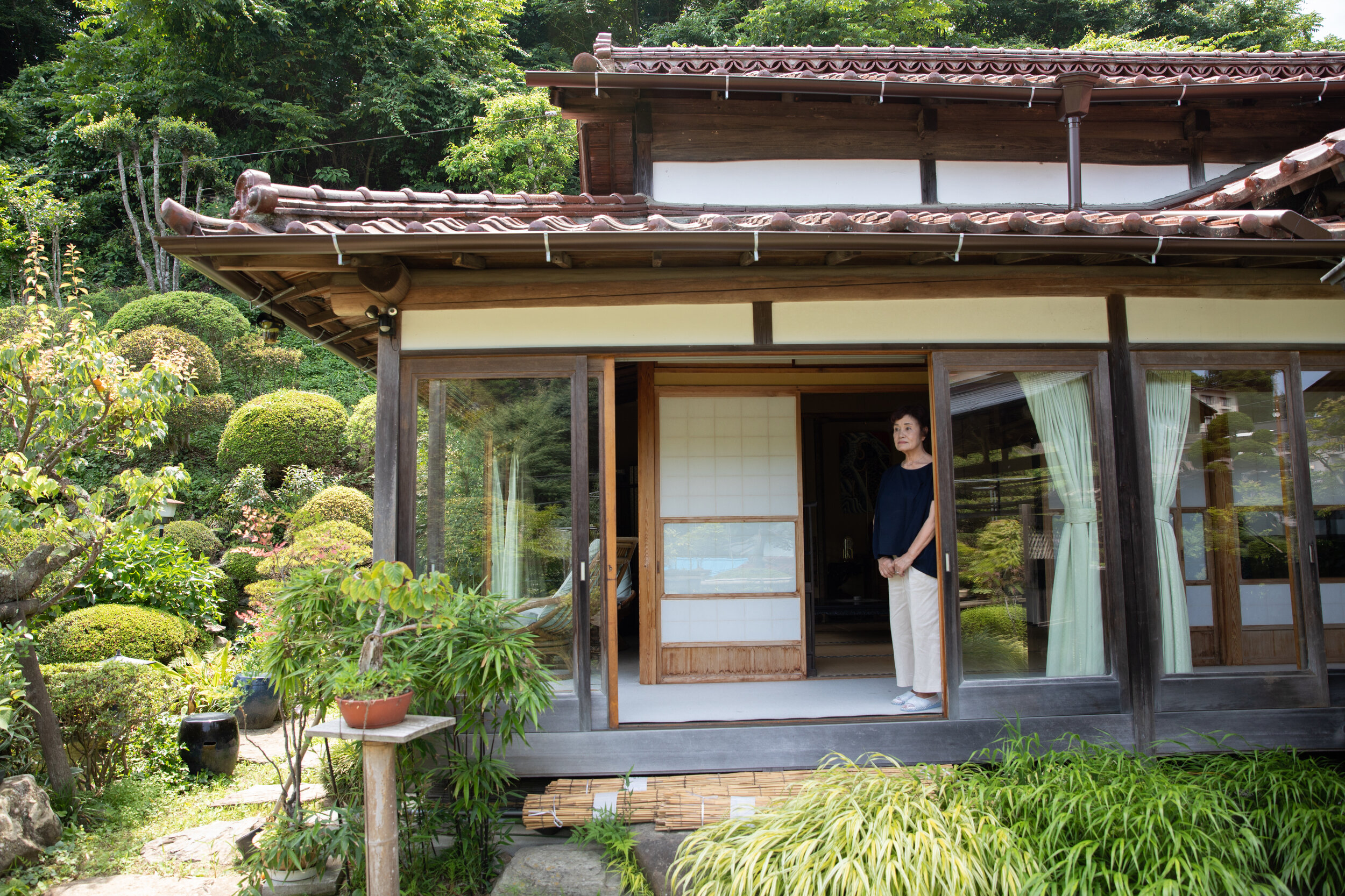  Last summer, longtime resident Yuko Sato stood outside her traditional Japanese home in the hills overlooking the town. Since the house remained intact right after the earthquake, she transformed it into a makeshift evacuation center. Luckily, she s