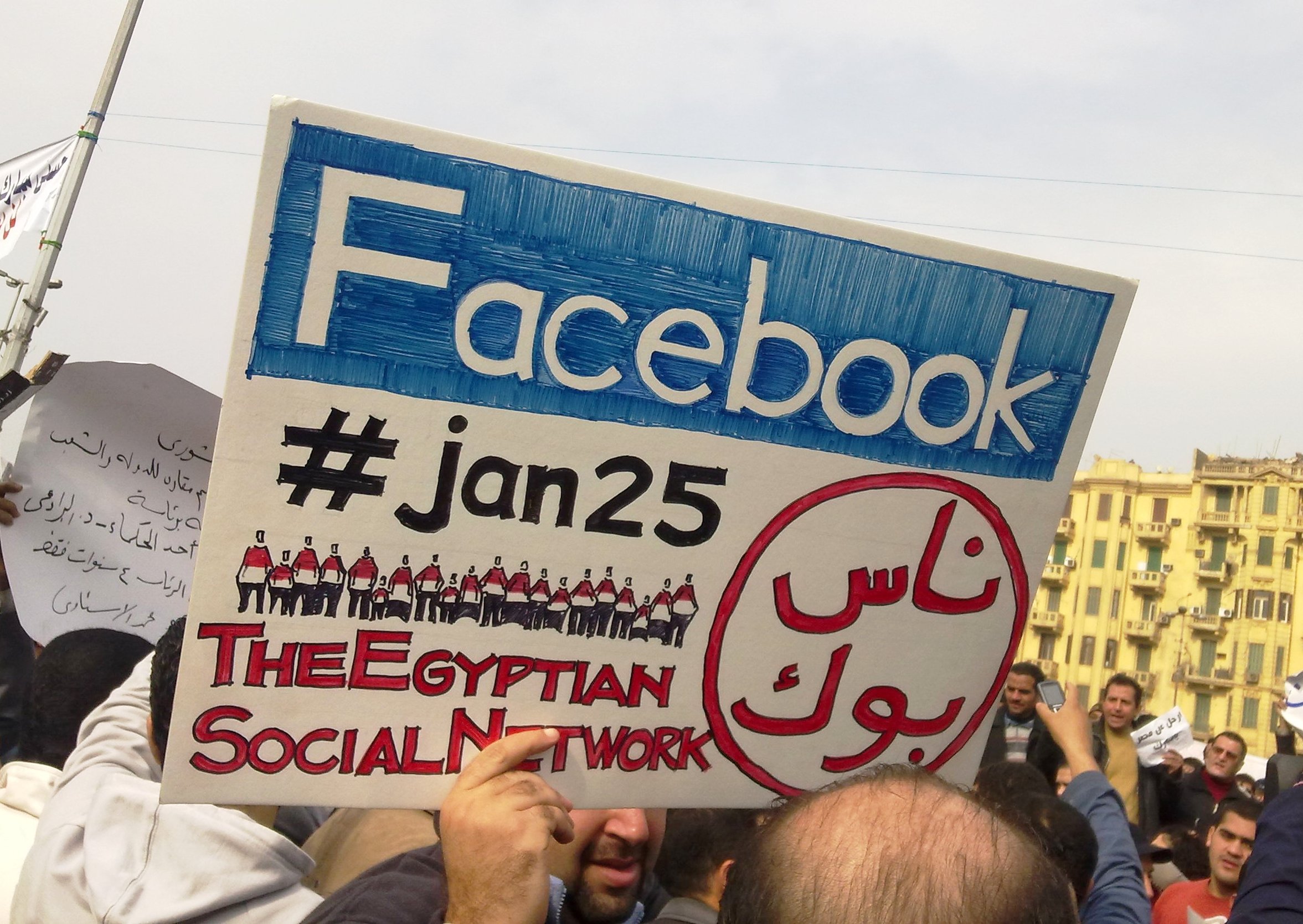 Un hombre sostiene un cartel con el hastagh de Twitter #jan25 (enero 25) y el logo de Facebook durante las protestas en El Cairo en 2011
