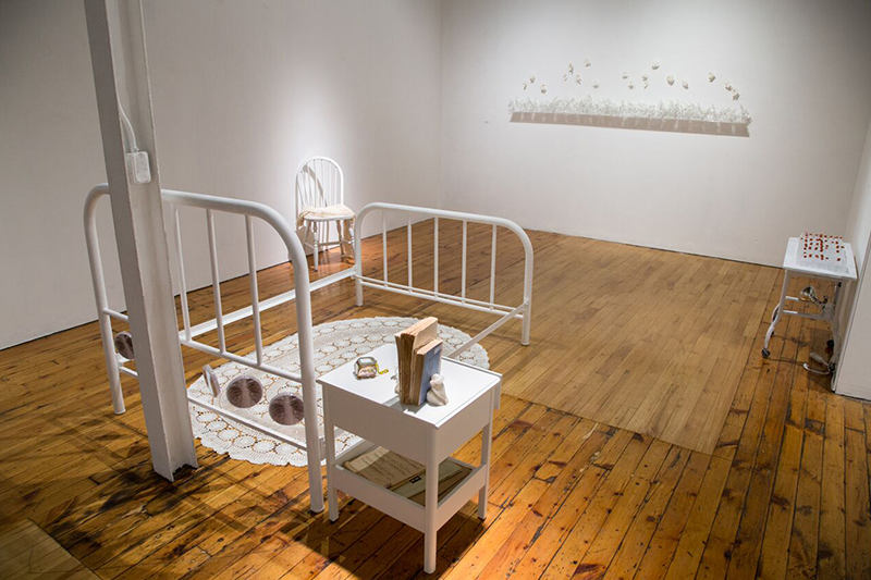   Contained  (installation),   2018 Bed, bedside table, chair, crocheted shawl by Louise while in sanitorium, her books and music piano music sheets, personal items, table cloth, petri dishes with ink drawing and X-ray of lungs with TB  