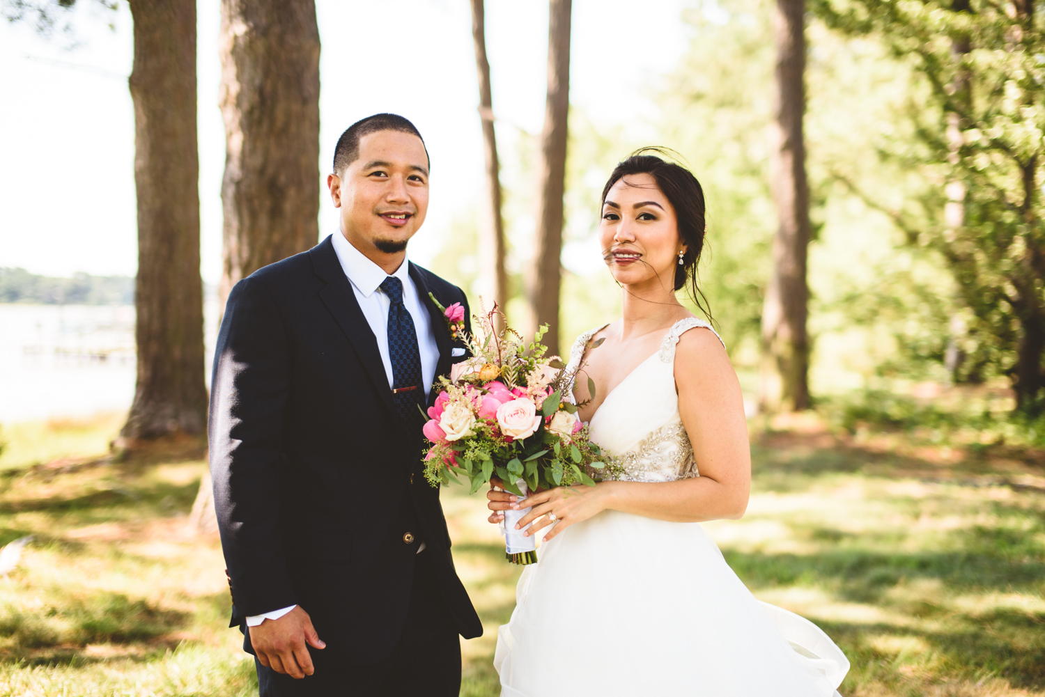 021 bride and groom looking at the camera in a small patch of trees near the ocean.jpg