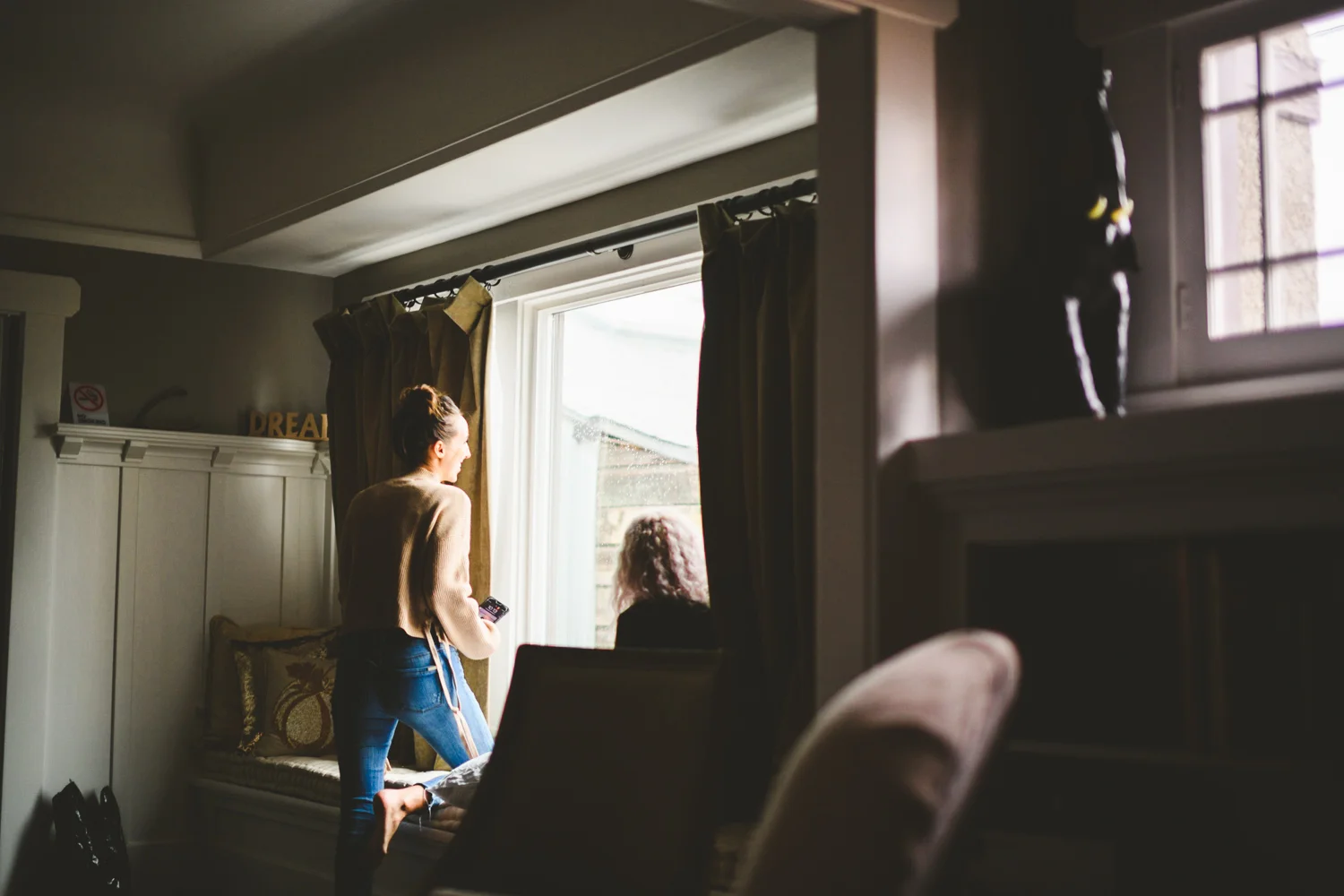 002 - bride laughs and gets ready near large window.jpg