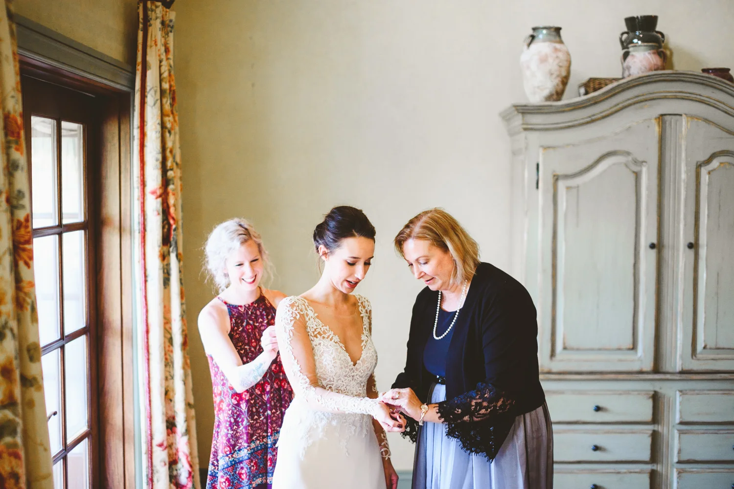 011 - mother of the bride and maid of honor help bride put on wedding dress.jpg