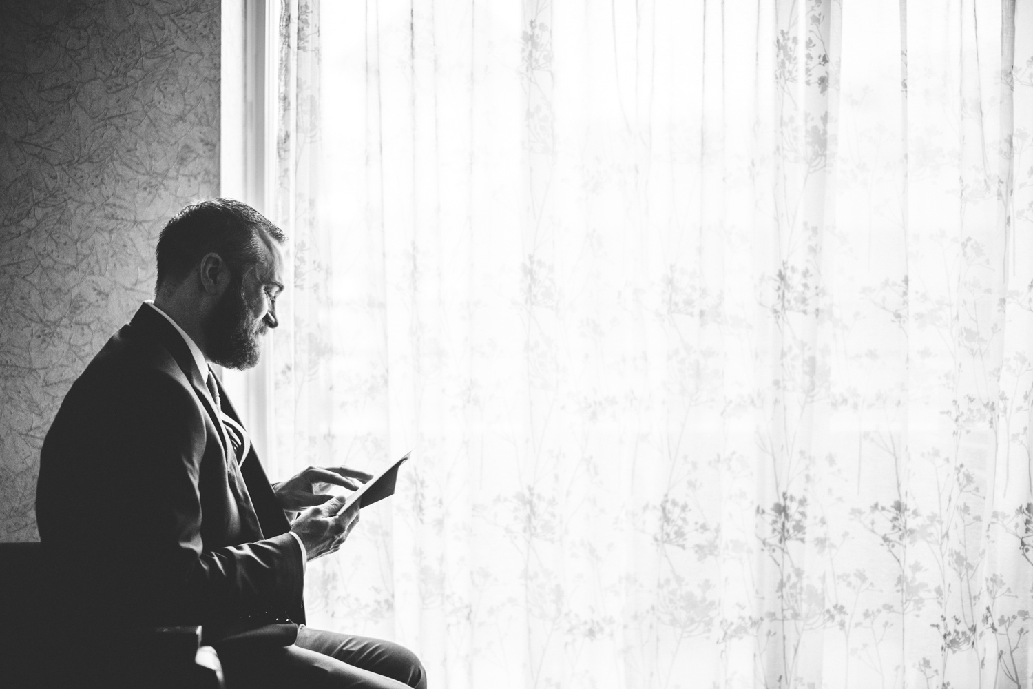 013 - black and white photo of groom smiling as he reads note from bride.jpg