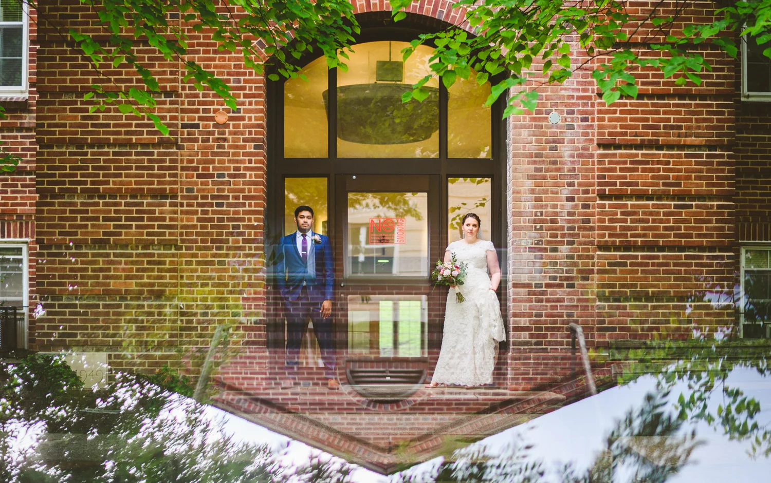 039 - reflection of bride and groom next to brick building.jpg