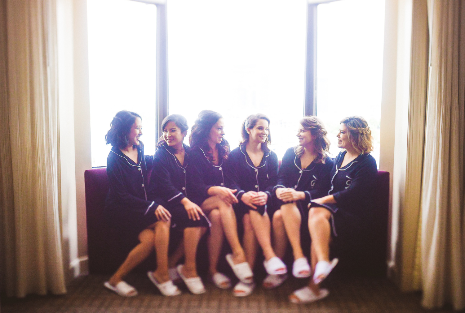 002 - beautiful bridesmaids and bride talking on purple couch with fun bridal gowns on.jpg