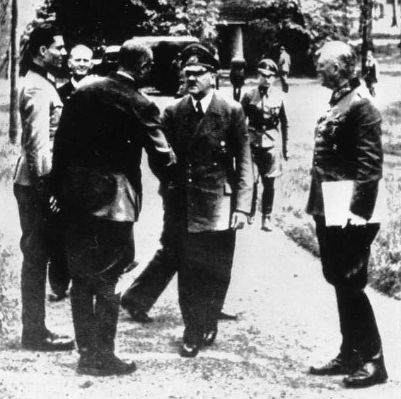Claus is on the left, standing at attention in front of Hitler.