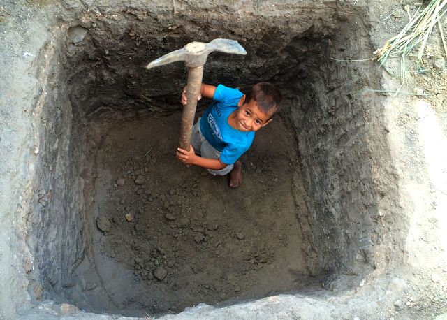 A young member of the El Pilon community helping to construct a pit toilet 