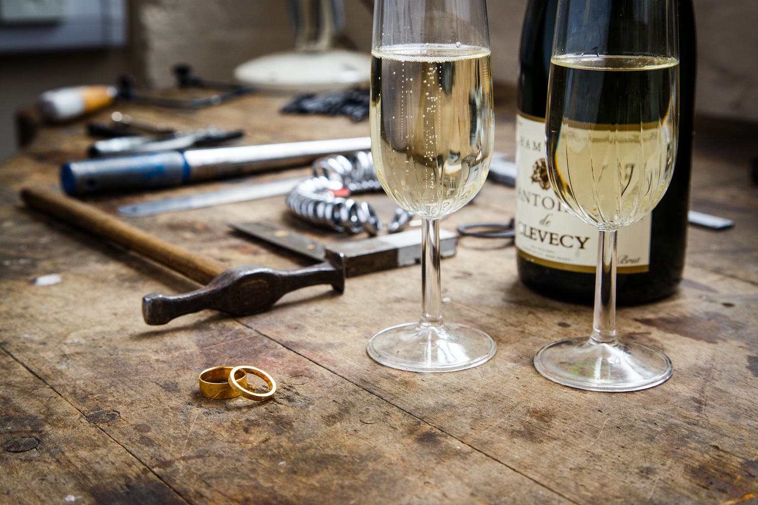 champagne and wedding rings on the jewellery bench with tools 