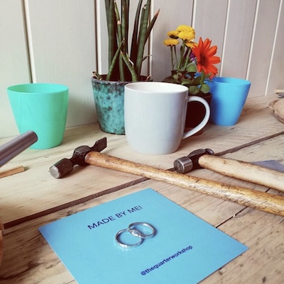 finished silver rings with hammer and card on jewellery bench 