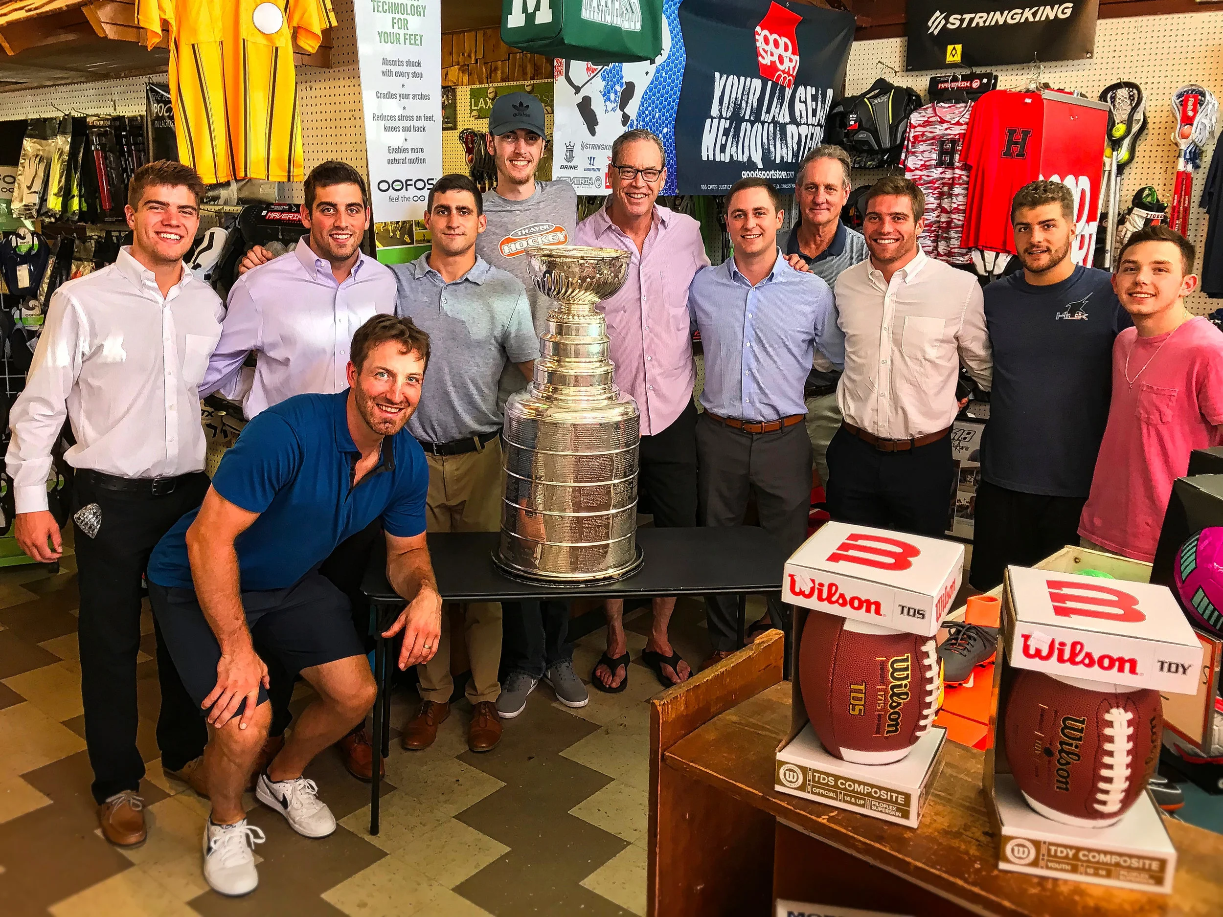 Austin Lyne (center with glasses) poses with current and past employees, The Stanley Cup and Brooks Orpik (front) of the world champion Washington Capitals.