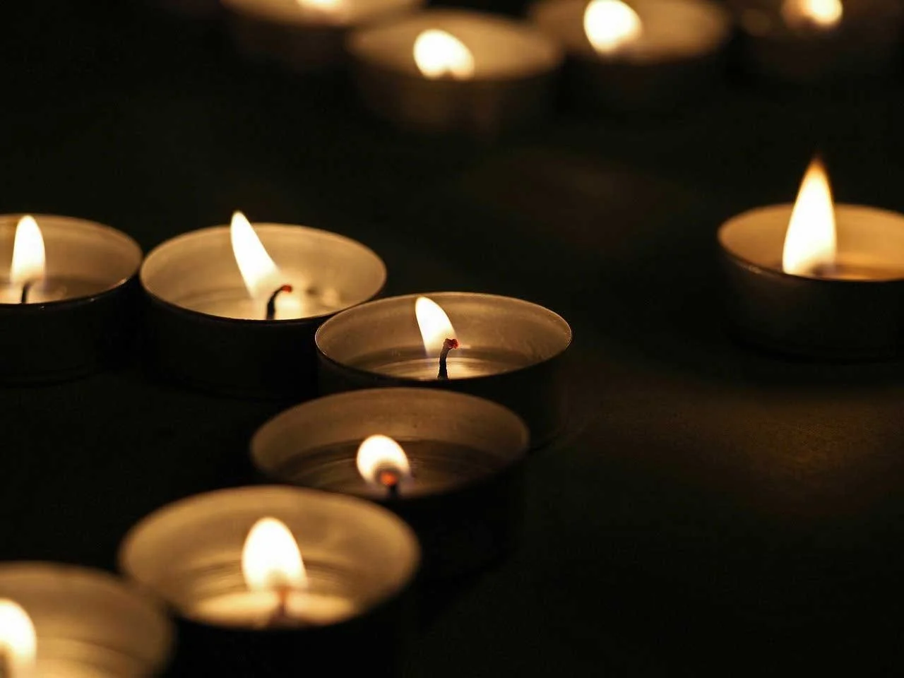 Lit Memorial Candles Glowing In A Dark Setting During A Funeral Service