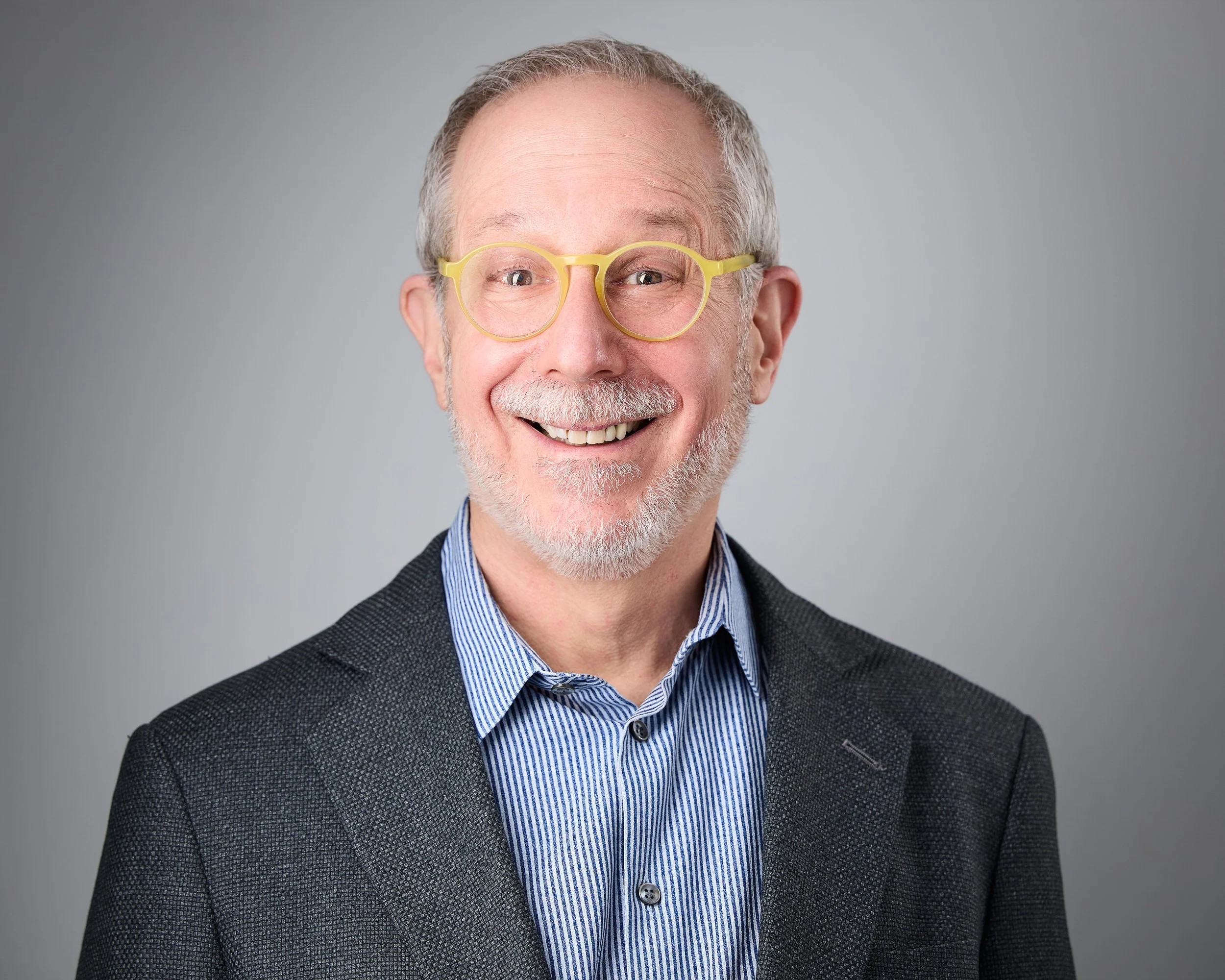 Man smiles at the camera showing an example of how senior professionals and executives aim to show approachability and authority in their headshots in 2026.