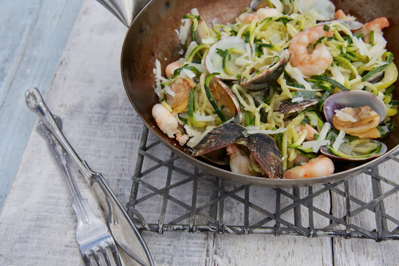 Seafood pasta with shrimp, mussels, and zucchini noodles in a skillet.
