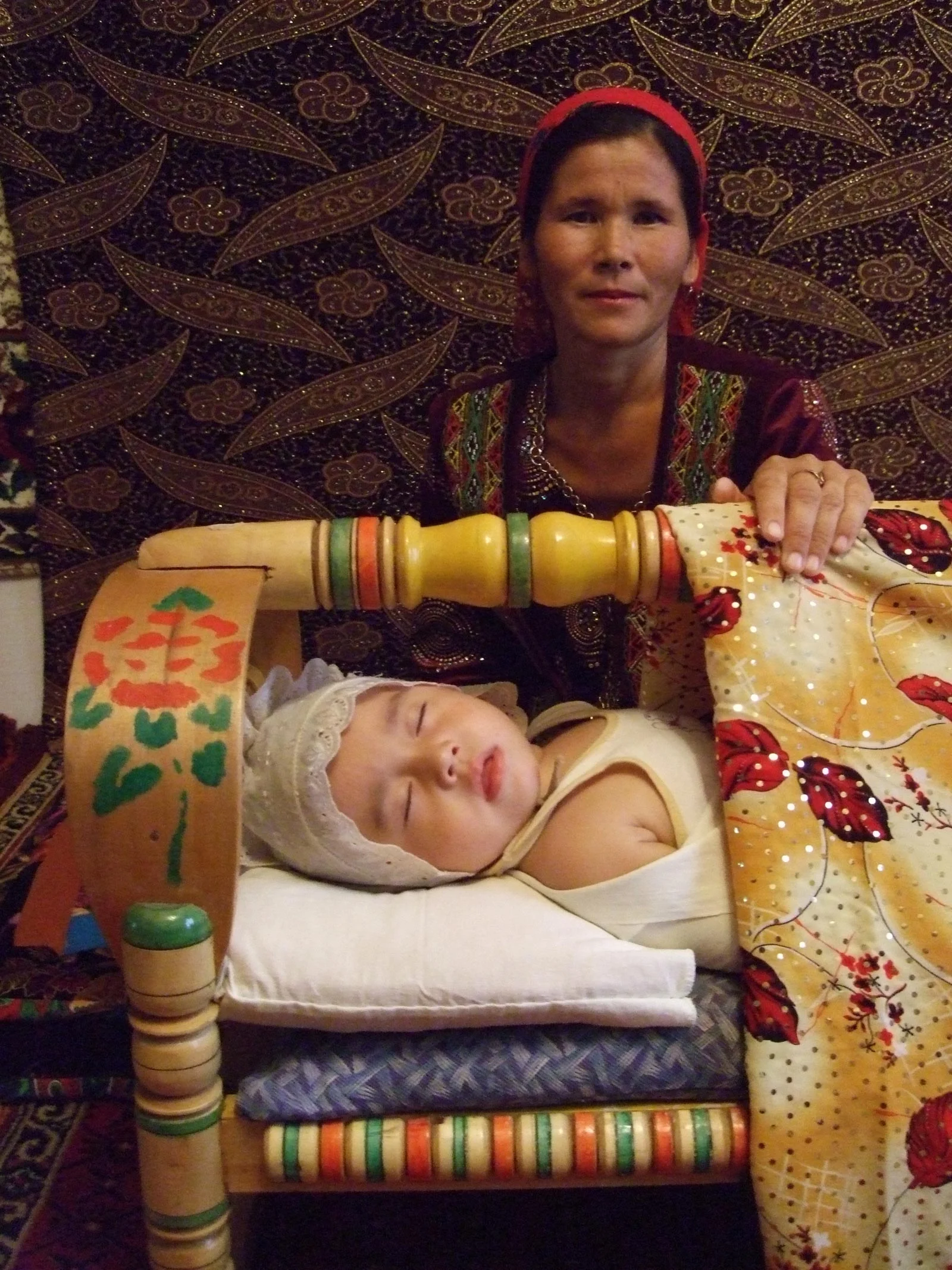 Enfant endormi dans un berceau traditionnel karakalpak