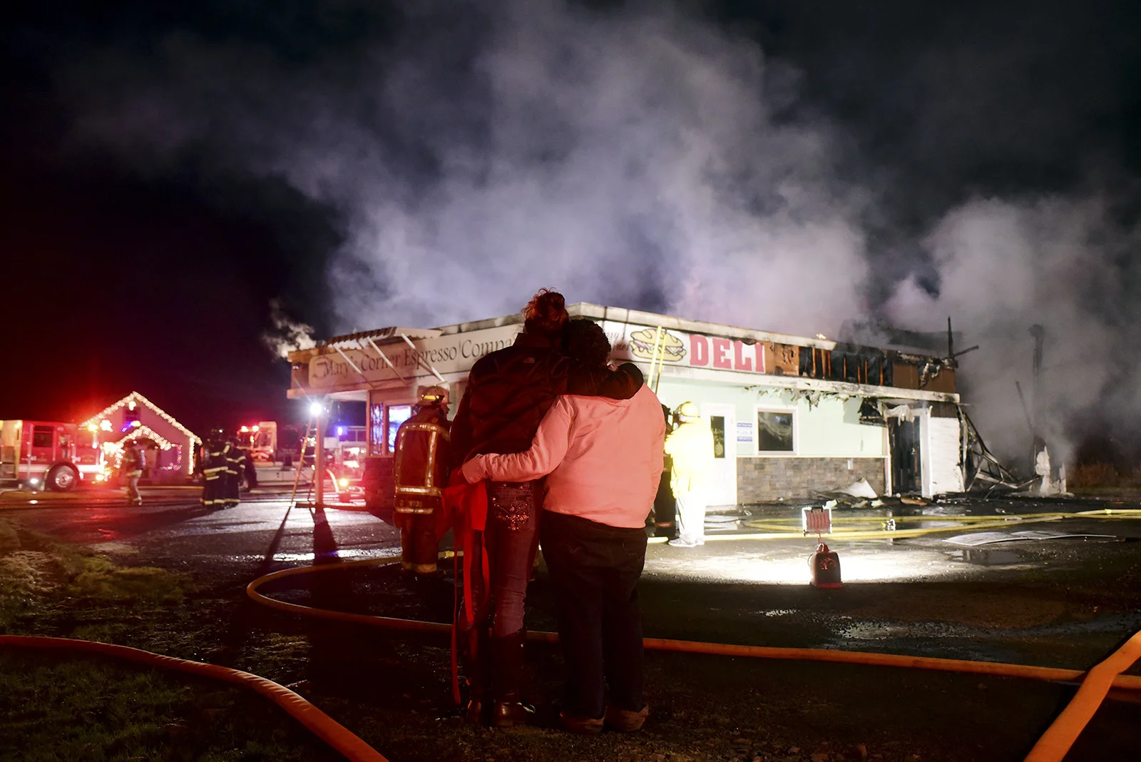 Liz Hill, owner of Mary's Corner Deli, and her daughter Taylor Anderson, left, embrace as they watch while firefighters battle a blaze at the restaurant and espresso stand on Tuesday, Dec. 2, 2014, at the intersection of U.S. Highway 12 and Jackson Highway south of Chehalis, Wash. No one was injured in the fire, but the building was completely destroyed.
