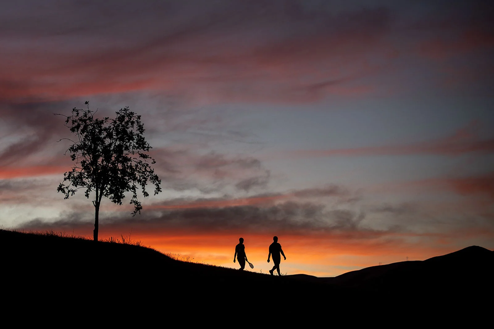 People walk along the Lewiston Levee Parkway Trail as the sun sets on Sunday, July 15, 2018, in Lewiston, Idaho.