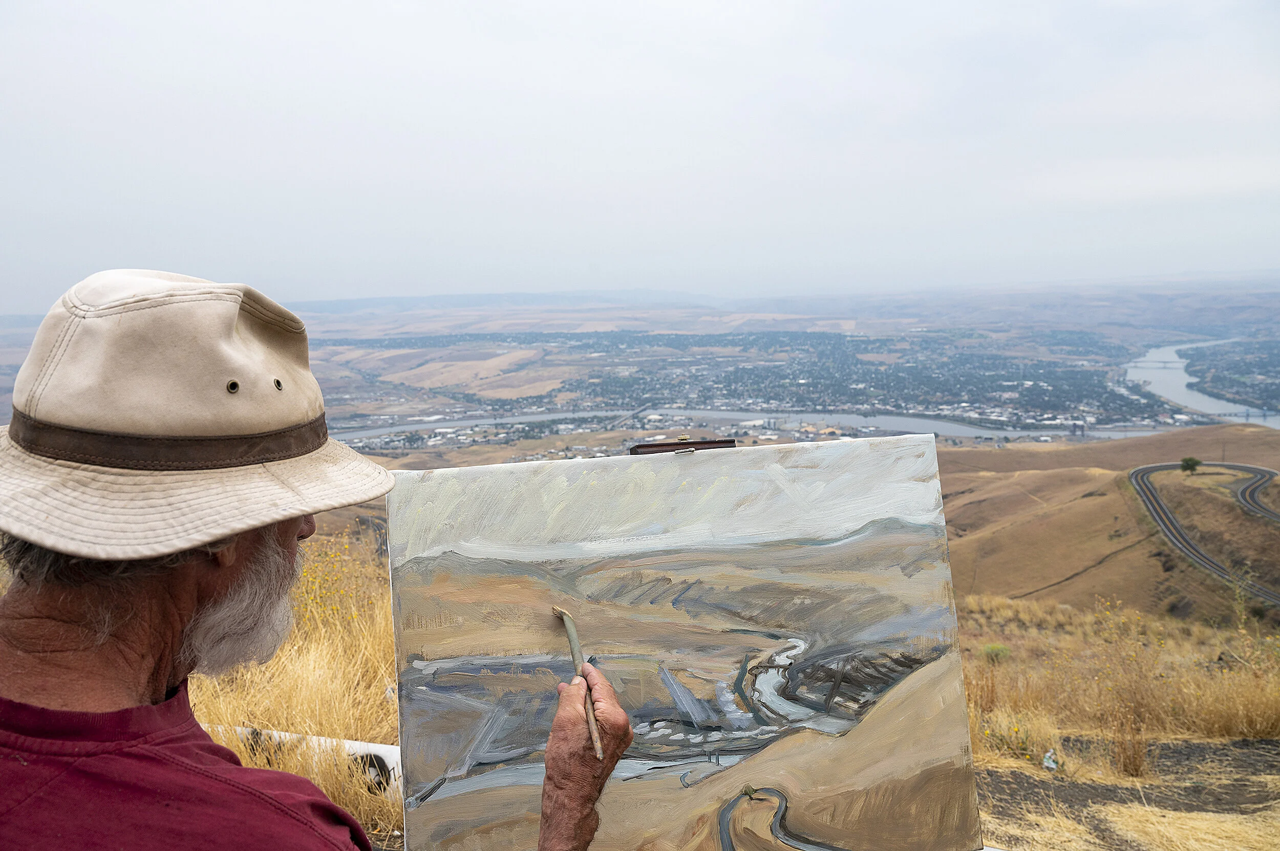  Despite the overcast and general haziness of the Lewiston-Clarkston Valley, Gary Meacham, of Silverton, Ore., moves his brush across the canvas of an oil painting he worked on from a scenic overlook atop the Lewiston Hill on Monday, Aug. 24, 2020. M
