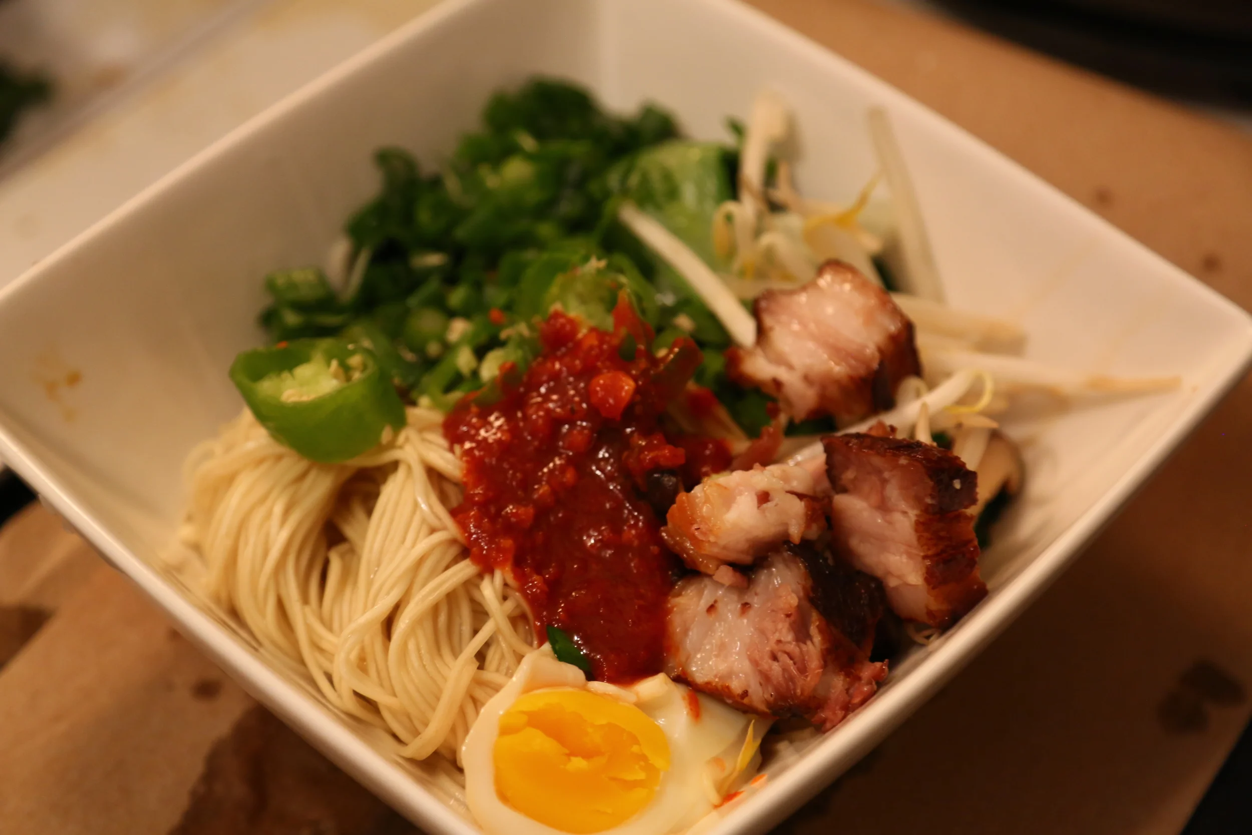 Fresh ramen noodles, pork belly marinated in sake, mirin and soy, sous-vided and then deep-fried, chives, extra-spicy Szechuan sauce (itself consisting of: fermented salted soybean, water, salt, wheat flour, chili, sugar, pickled vegetables, soy bean oil, garlic, salt, peanut, onion, sesame oil, yeast extract, maize starch), sous-vided egg marinated in juices from the pork belly, jalapenos, mayu (blackened garlic in sesame oil), bean sprouts, blanched bok choy and blanched Shanghai choy.