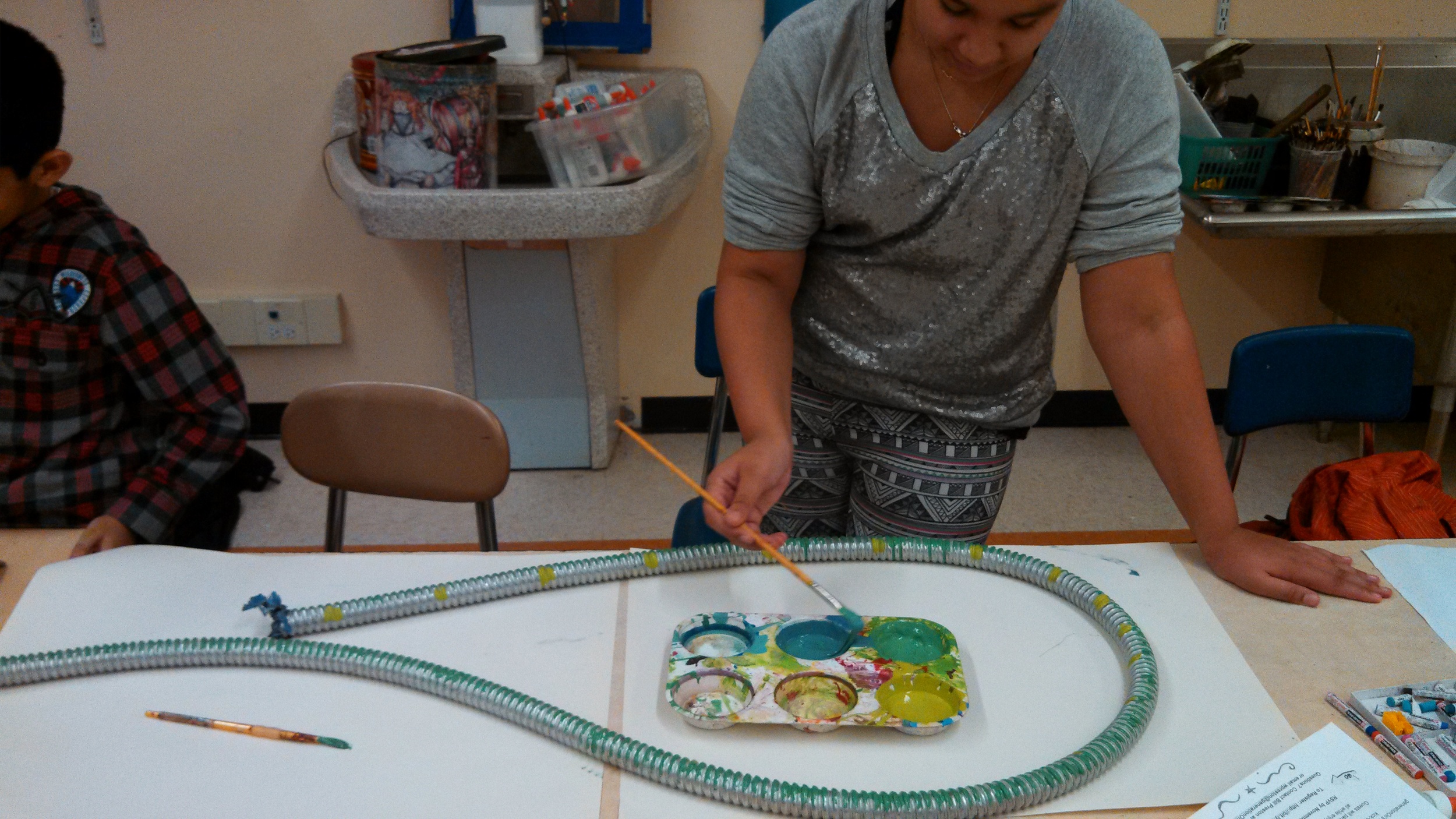 Students paint scrap metal for an outdoor installation, inspired by Tyree Guyton's exhibition.