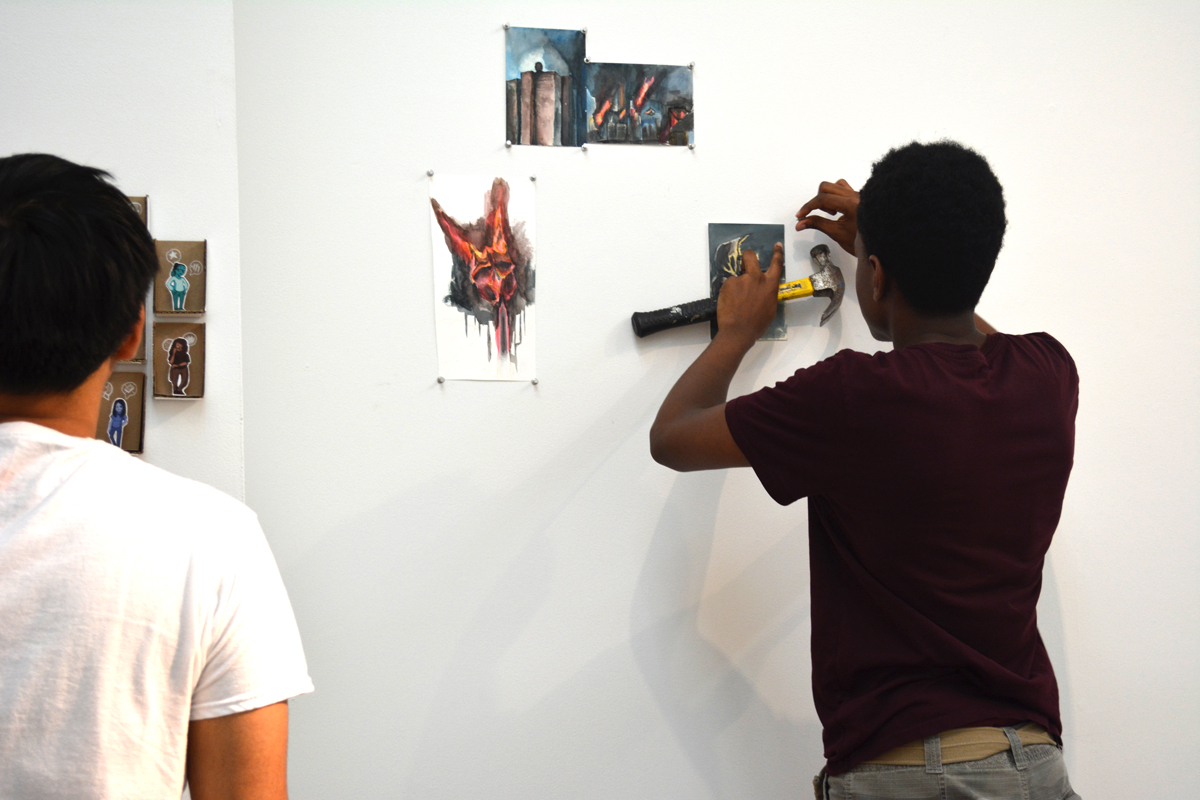 jumpstART artists installing their work in the CUE gallery
