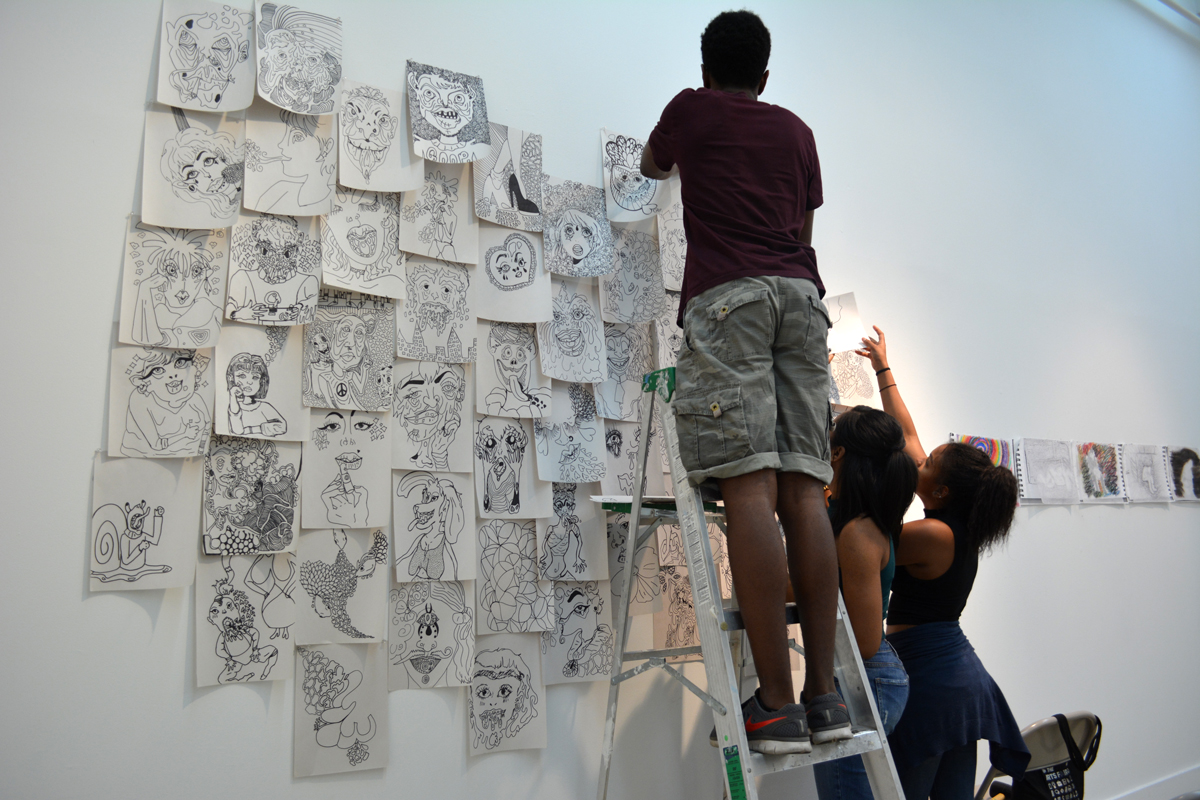jumpstART artists installing their work in the CUE gallery